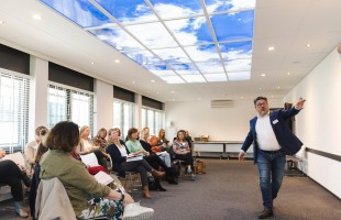 Hans Etman, spreker tijdens bijeenkomst Logeion met volle zaal deelnemers